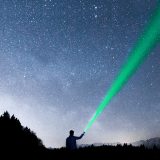 Ein Mann strahlt mit einer Taschenlampe in den Sternenhimmel auf der Suche nach einer »Marketingstrategie«