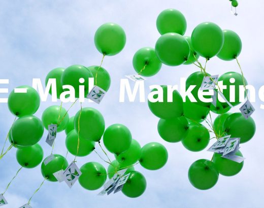 Grüne Luftballons mit einer grün-gelblichen Schnurr, an dem eine Postkarte befestigt steht. In großer Schrift steht mitten auf dem Bild geschrieben »E-Mail-Marketing«