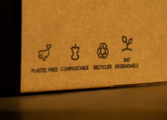 Trend Nachhaltigkeit – Ein nachhaltiger Karton mit vier Symbolen, die beschreiben, dass der Karton plastikfrei, kompostierbar, recycelt werden kann und biologisch abbaubar