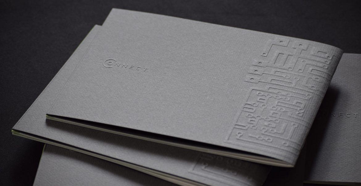 Mehrere dunkelgraue Broschüren liegen aufeinander gestapelt aufeinander. Auf dem Cover ist »LuxConnect« geprägt.