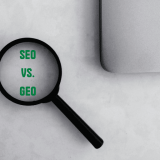 Ein Lupe liegt auf einem Schreibtisch und zeigt auf einen Text. Der Text lautet: SEO vs. GEO.